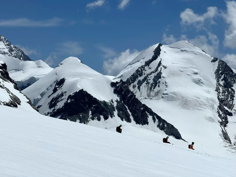 Ski-tourers crossing a snowfield below the high peaks