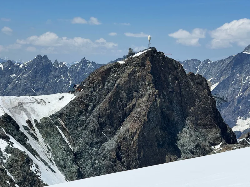 A rocky summit station ringed by snow-capped Alpine peaks