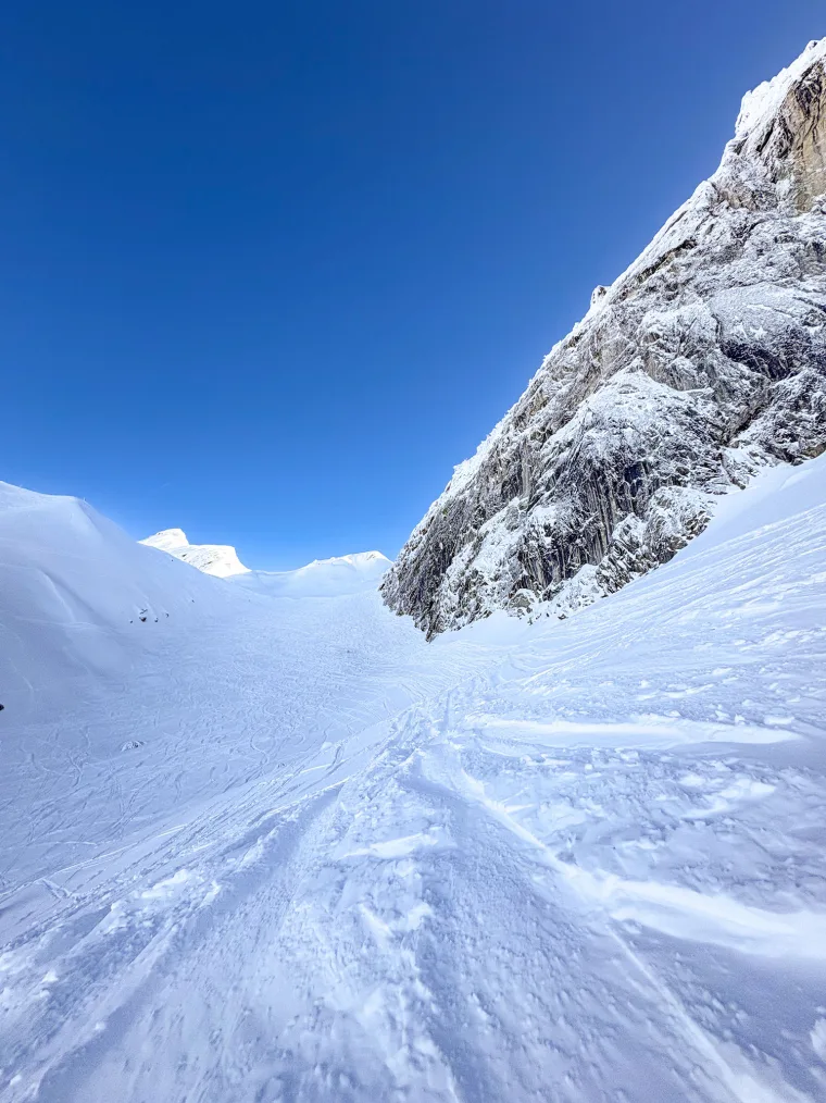 Looking up a snow couloir toward a deep-blue sky
